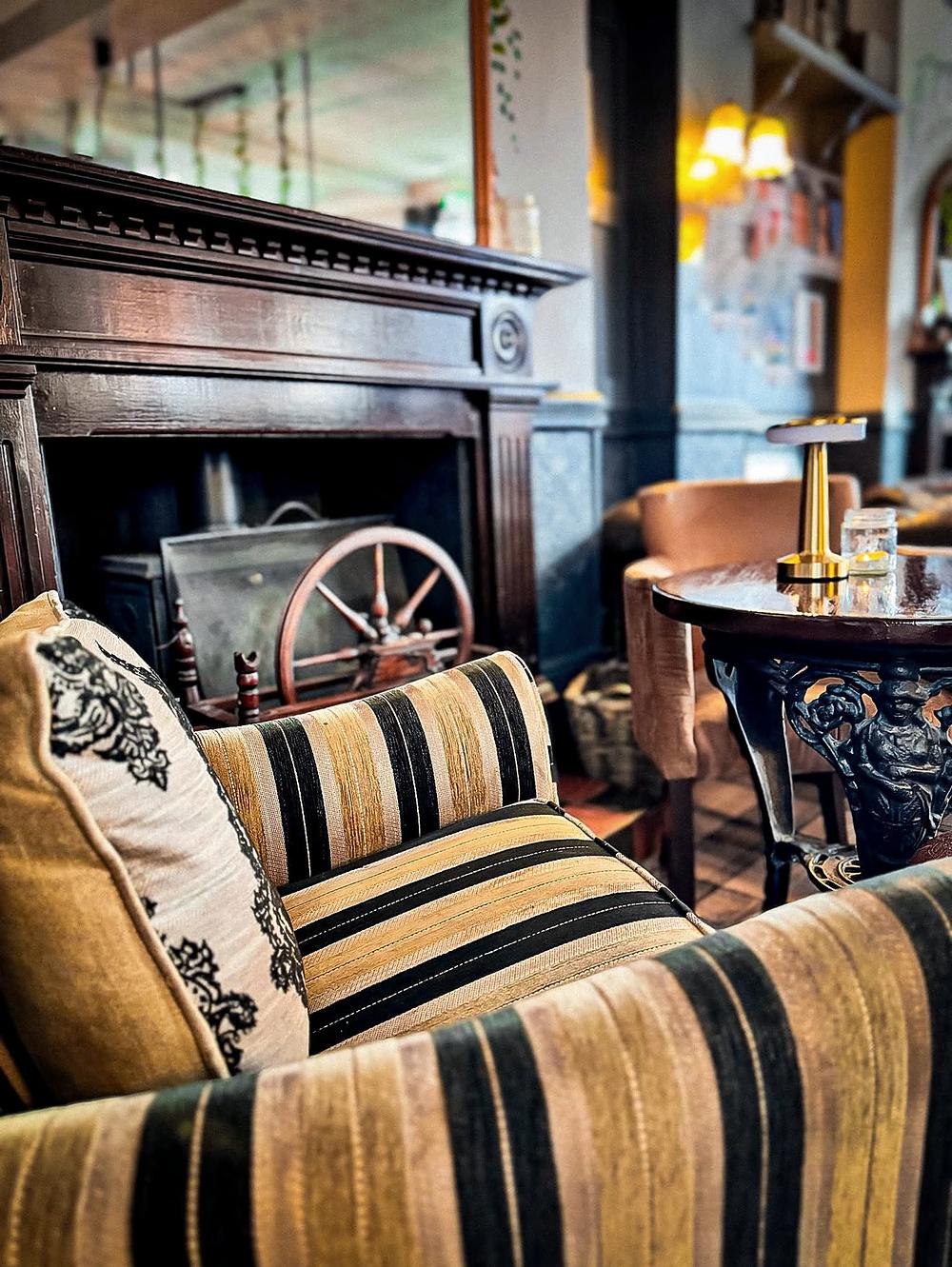 Striped armchairs and cushions by the fireplace in the lounge at The Summerfield