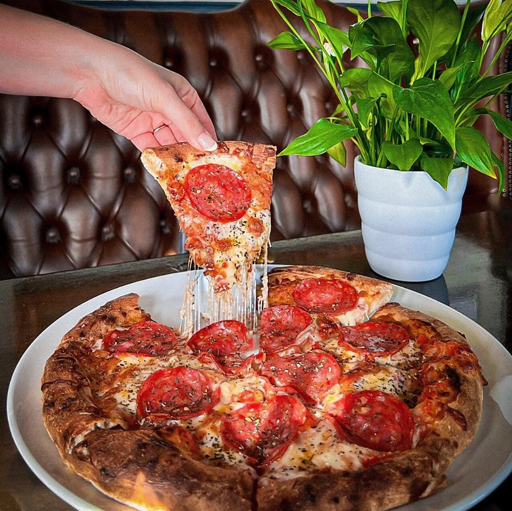 A slice being pulled from a stonebaked pepperoni pizza at The Summerfield