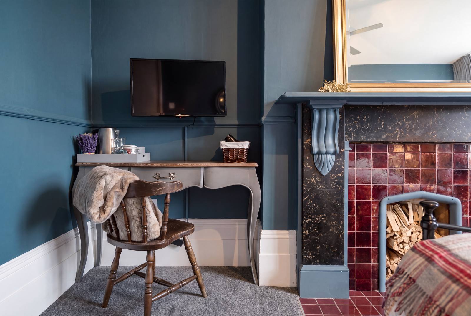 A writing desk and chair beside a tiled Victorian fireplace